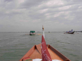 Prua con bandiera Vogalonga 2011 con vista su barche davanti, laguna e cielo